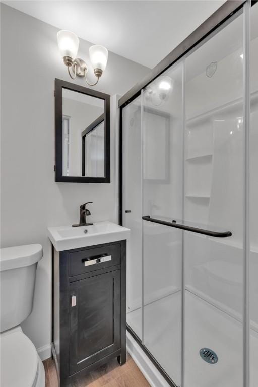 full bath featuring wood finished floors, a shower stall, toilet, and vanity