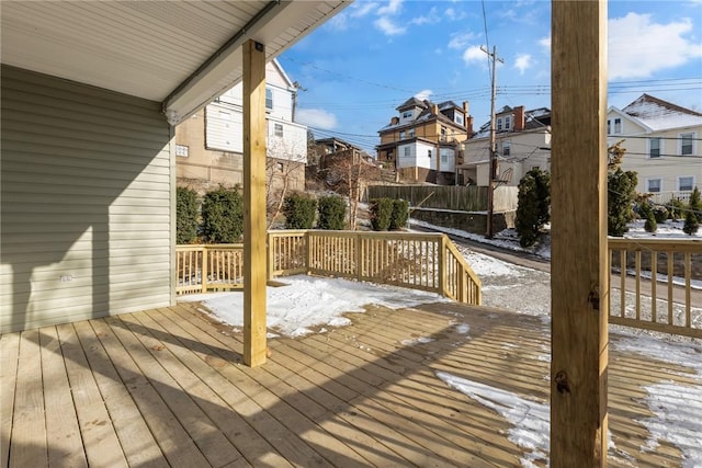 snow covered deck with a residential view and fence