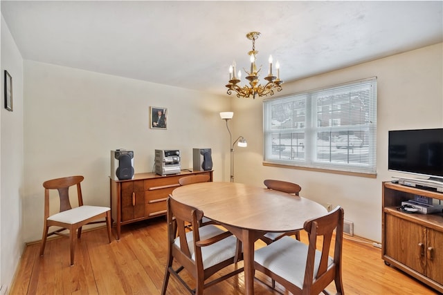 dining room with light wood-style floors and an inviting chandelier