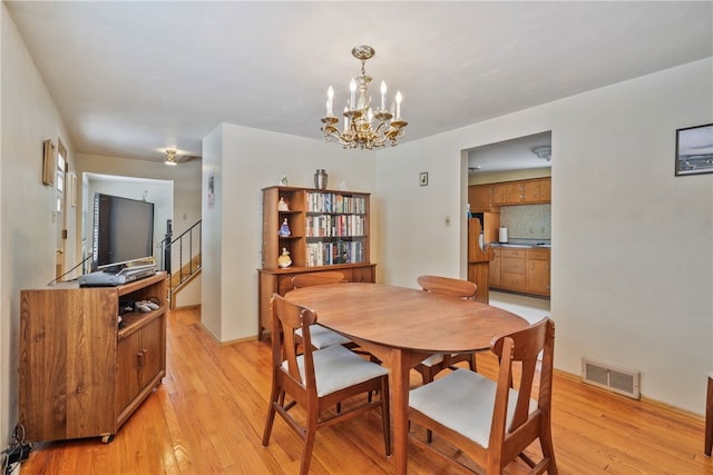 dining room featuring stairs, light wood-style flooring, visible vents, and a notable chandelier