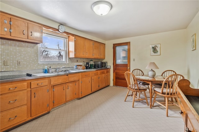 kitchen with light countertops, brown cabinets, decorative backsplash, light floors, and stainless steel microwave