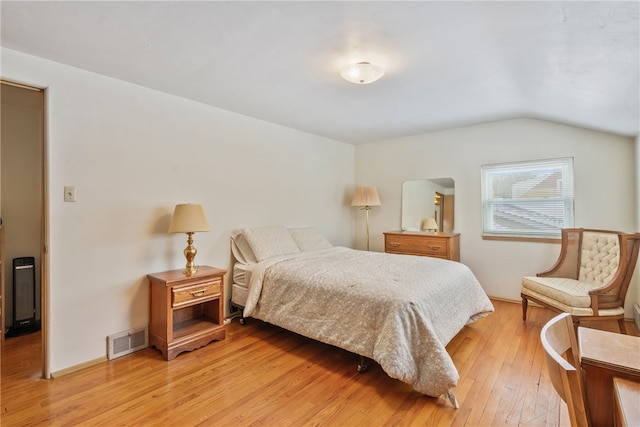 bedroom featuring vaulted ceiling, light wood-style flooring, and visible vents