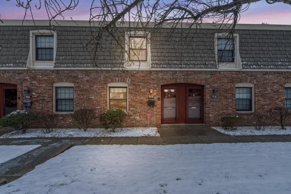 view of front of house with mansard roof and brick siding