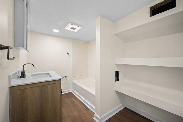 bathroom with wood finished floors, visible vents, baseboards, vanity, and a tub