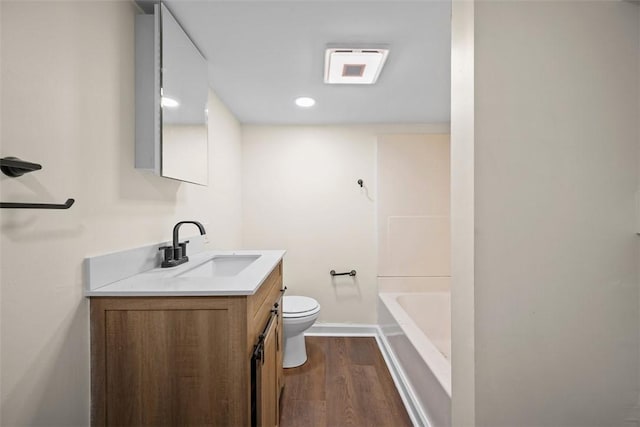 bathroom with toilet, wood finished floors, visible vents, vanity, and baseboards