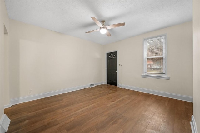 unfurnished room featuring visible vents, baseboards, a ceiling fan, wood finished floors, and a textured ceiling