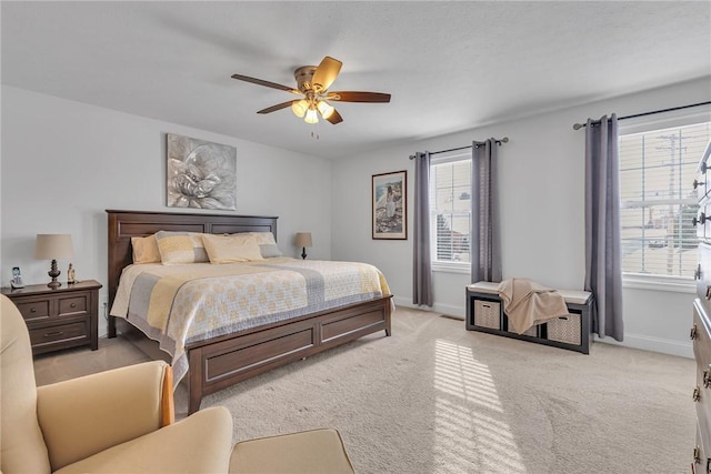 bedroom with multiple windows, light colored carpet, and baseboards