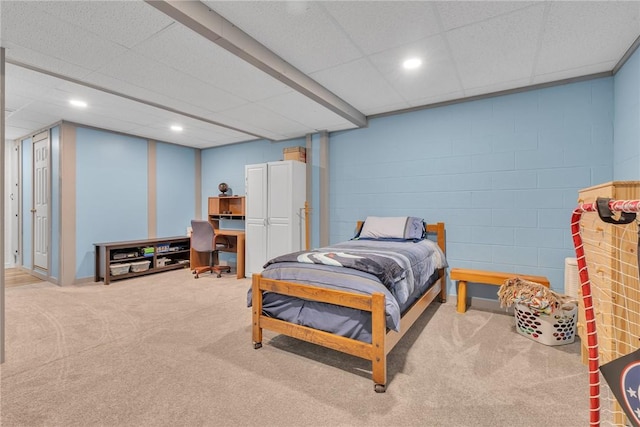 bedroom featuring concrete block wall, light colored carpet, and recessed lighting