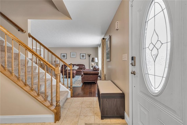 entrance foyer featuring stairs, baseboards, and light tile patterned flooring