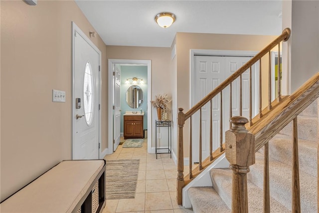 foyer entrance featuring light tile patterned floors, stairs, and baseboards