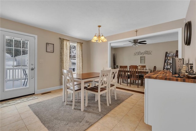 dining room with light tile patterned floors, visible vents, baseboards, and ceiling fan with notable chandelier