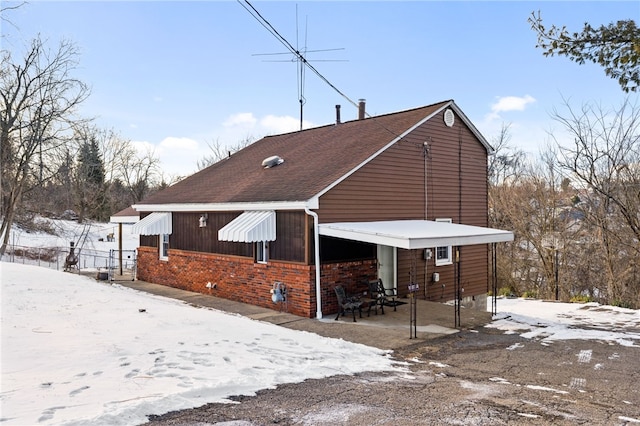 view of snowy exterior with brick siding