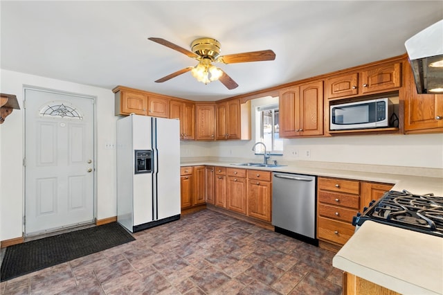 kitchen with brown cabinets, stainless steel appliances, light countertops, a sink, and exhaust hood