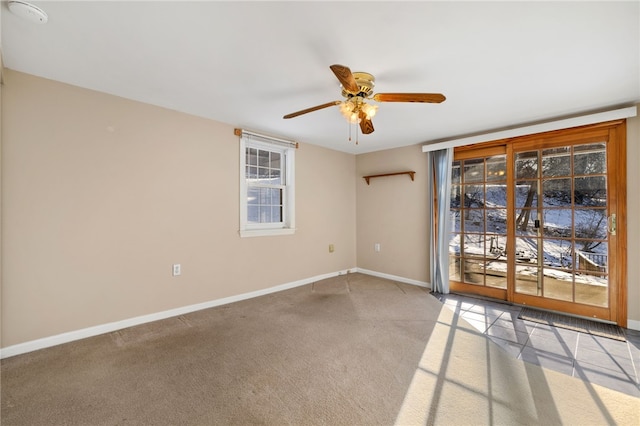 carpeted spare room with a ceiling fan and baseboards