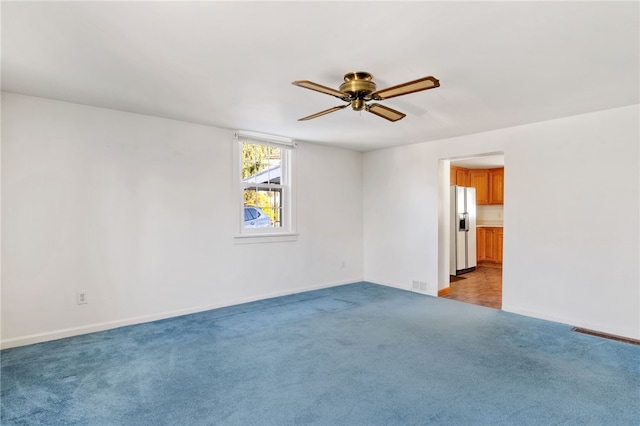 spare room with a ceiling fan, light carpet, visible vents, and baseboards