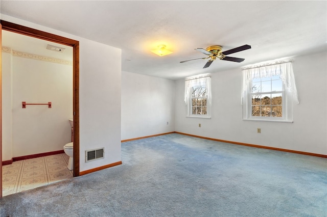 empty room featuring a ceiling fan, baseboards, visible vents, and carpet flooring