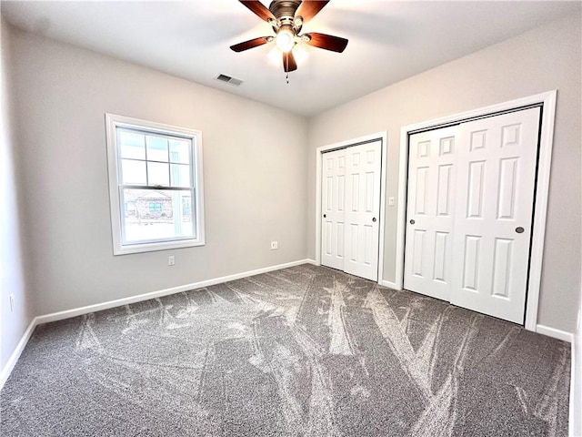 211 Ruby Dr, Menallen Twp, PA 15401 - unfurnished bedroom featuring visible vents, two closets, dark colored carpet, baseboards, and ceiling fan