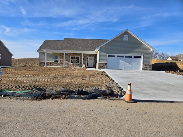 view of front of house with an attached garage, stone siding, and concrete driveway