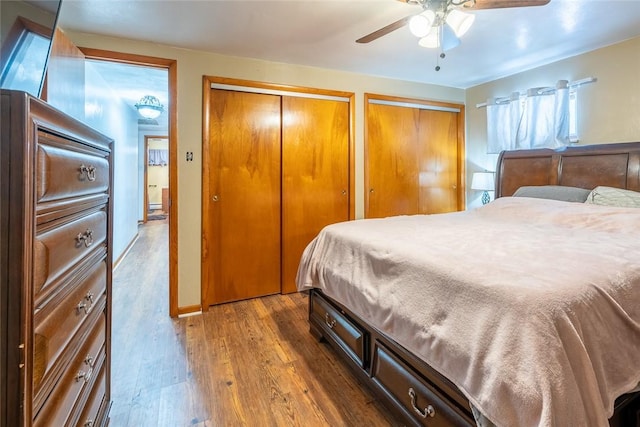 bedroom featuring ceiling fan, dark wood finished floors, and multiple closets