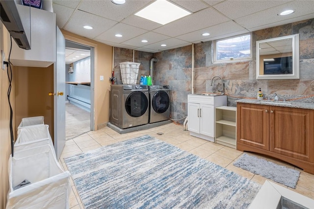 clothes washing area with washer and dryer, a sink, tile walls, and light tile patterned floors