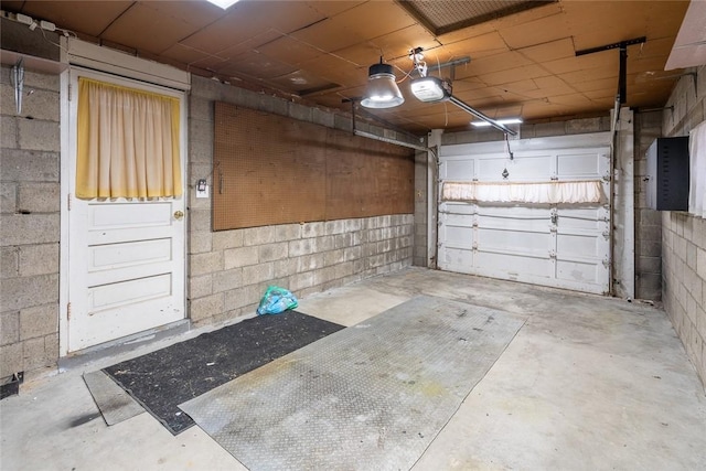 garage with a garage door opener and concrete block wall