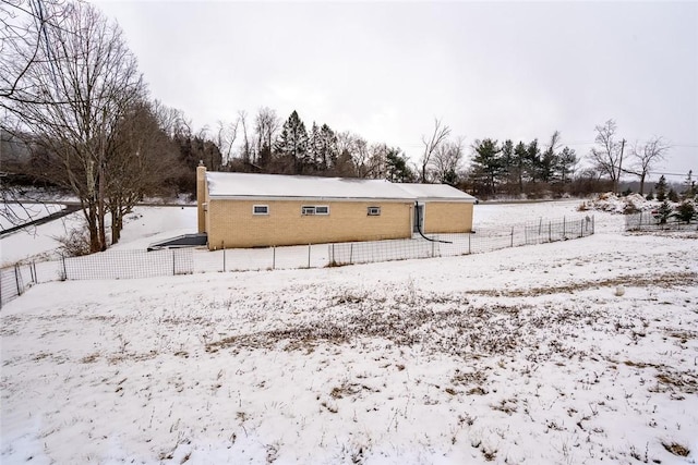 snow covered property with fence and a chimney