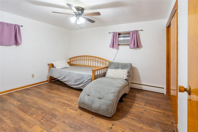 bedroom with dark wood-style floors, a closet, baseboards, and baseboard heating