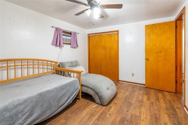 bedroom featuring a ceiling fan, a closet, baseboards, and wood finished floors