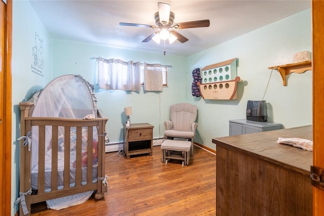 bedroom with baseboards, a baseboard radiator, ceiling fan, wood finished floors, and a baseboard heating unit