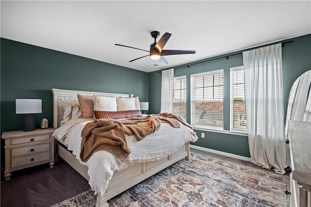 bedroom with ceiling fan, dark colored carpet, and baseboards