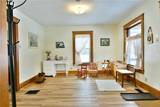 sitting room with light wood-style flooring, visible vents, and baseboards