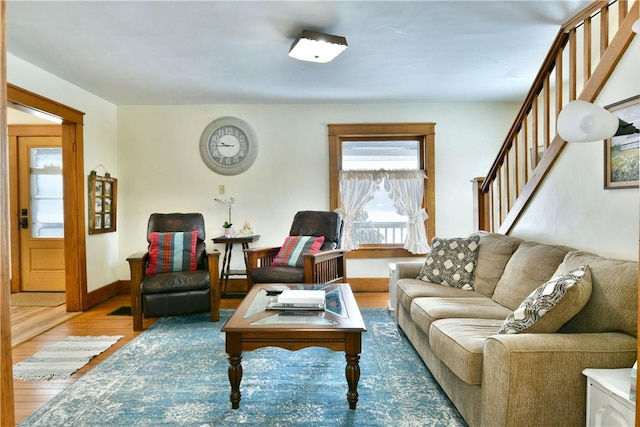 living room featuring baseboards, stairway, and wood finished floors