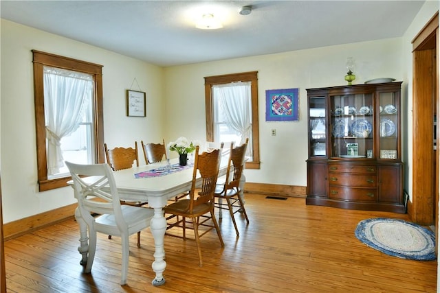 dining space featuring visible vents, light wood-style flooring, and baseboards