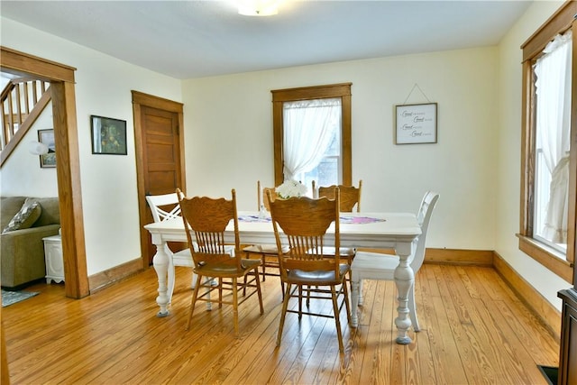 dining room featuring stairs, light wood-type flooring, and baseboards