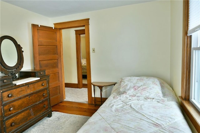 bedroom featuring light wood-style floors, multiple windows, and baseboards