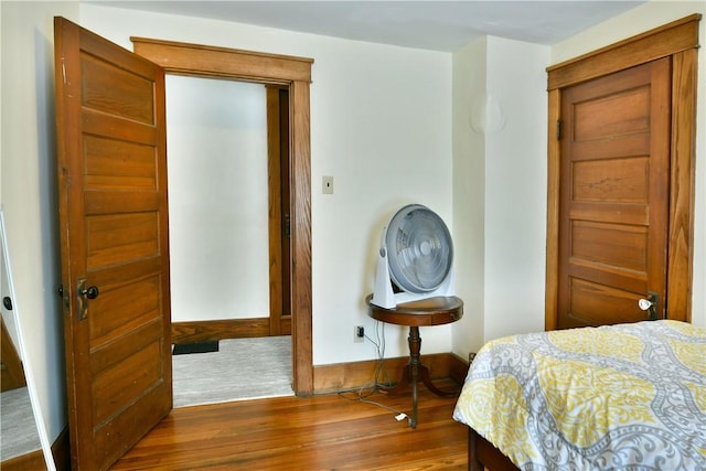 bedroom with dark wood-type flooring and baseboards