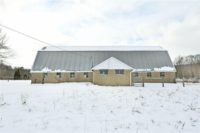 snow covered rear of property featuring metal roof