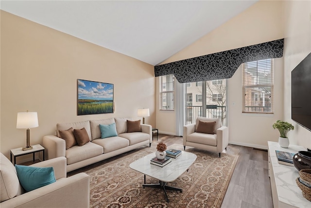 living room featuring lofted ceiling, wood finished floors, and baseboards