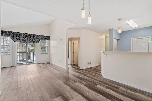 unfurnished living room with lofted ceiling, wood finished floors, visible vents, and baseboards