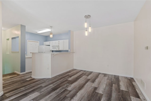 kitchen with a peninsula, white appliances, white cabinets, light countertops, and pendant lighting