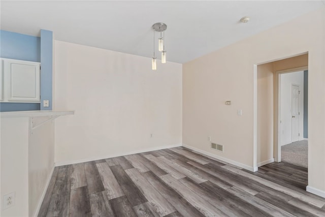 unfurnished dining area with visible vents, baseboards, and wood finished floors