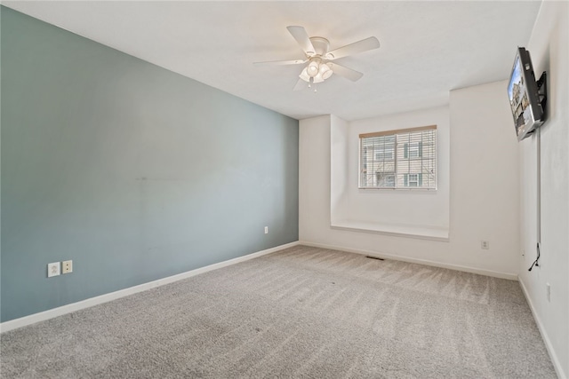 carpeted spare room with ceiling fan and baseboards