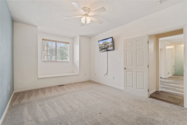 empty room with a ceiling fan, light colored carpet, and baseboards