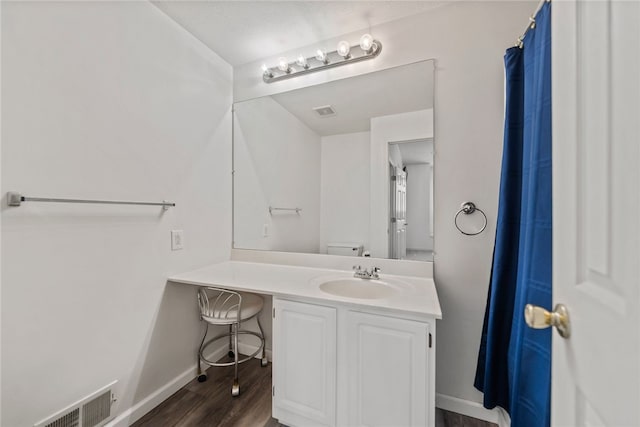 bathroom featuring visible vents, toilet, vanity, wood finished floors, and baseboards