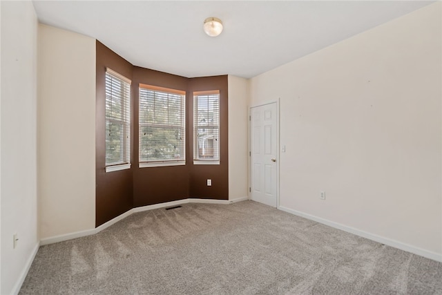 unfurnished room featuring carpet floors, visible vents, and baseboards