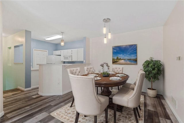 dining area featuring dark wood-style flooring and baseboards