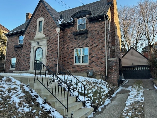 view of front of property with a chimney, a detached garage, and brick siding