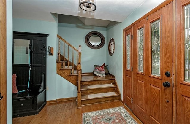 entryway with light wood finished floors, stairs, and baseboards