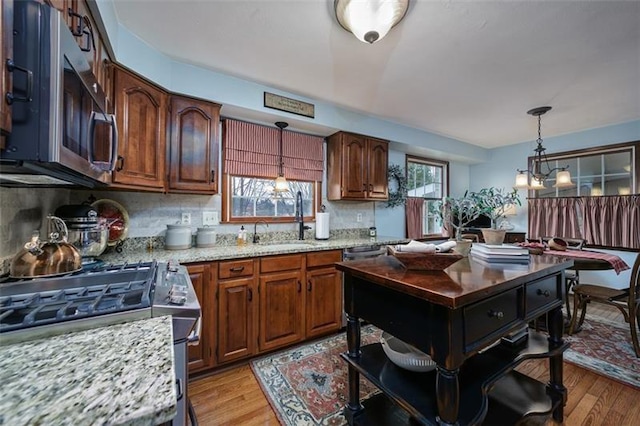 kitchen featuring hanging light fixtures, appliances with stainless steel finishes, a sink, and a healthy amount of sunlight