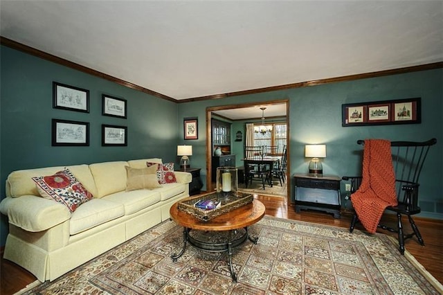 living area featuring ornamental molding, a chandelier, baseboards, and wood finished floors